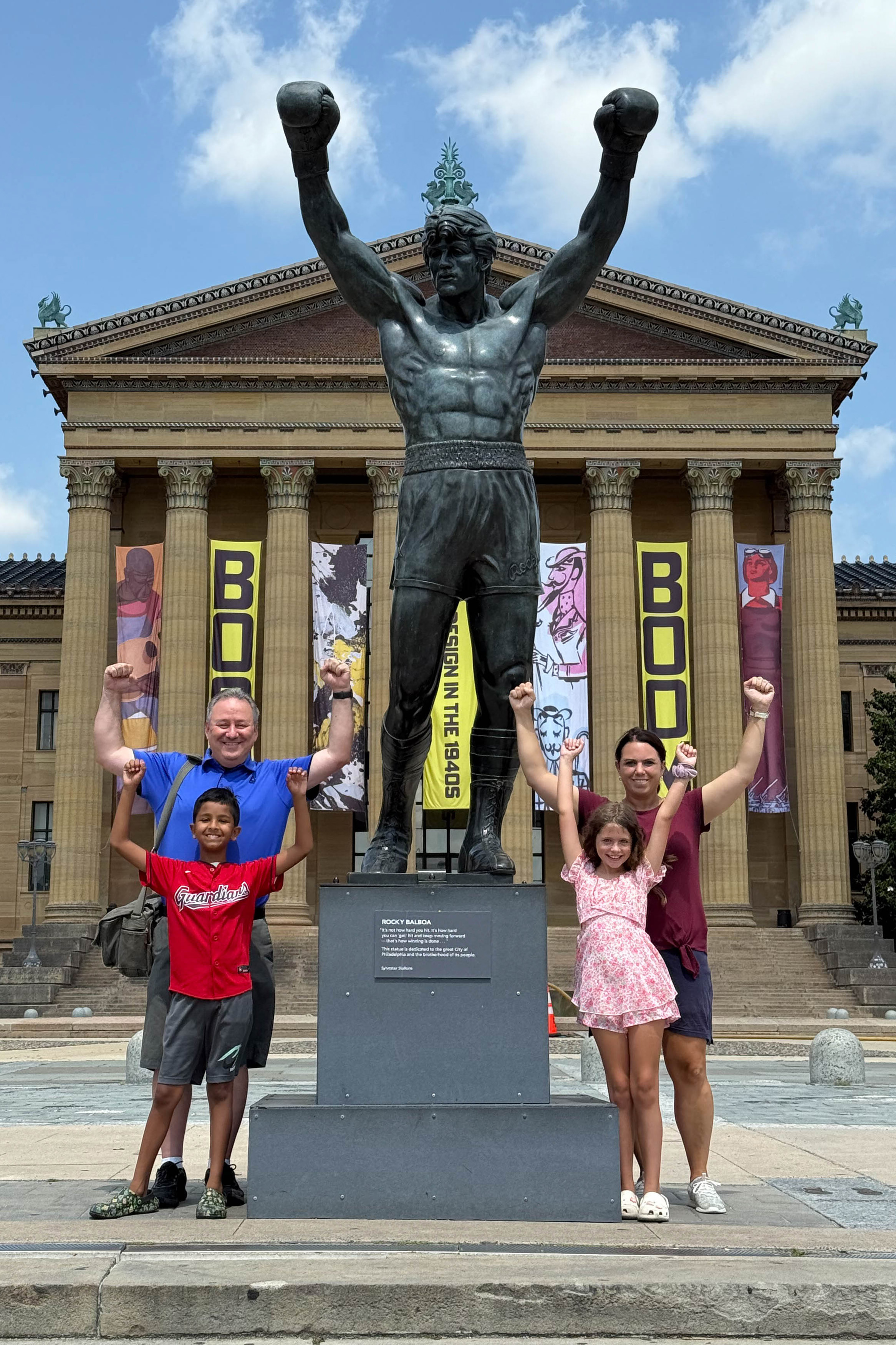 Our family excitedly posing with Sylvester Stallone's personal Rocky Statue at the top of the iconic Rocky Steps in 2025.