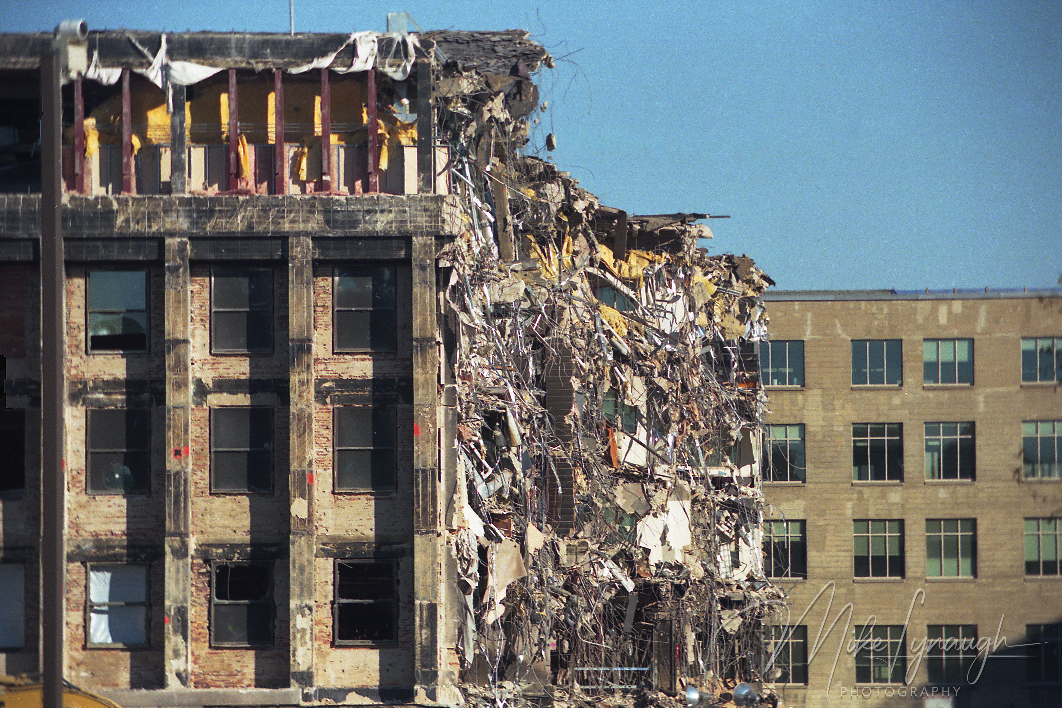 Detailed close-up showing a sheared outer wall section of the Pentagon with exposed brickwork, dangling concrete rebar, and intact windows next to the breach