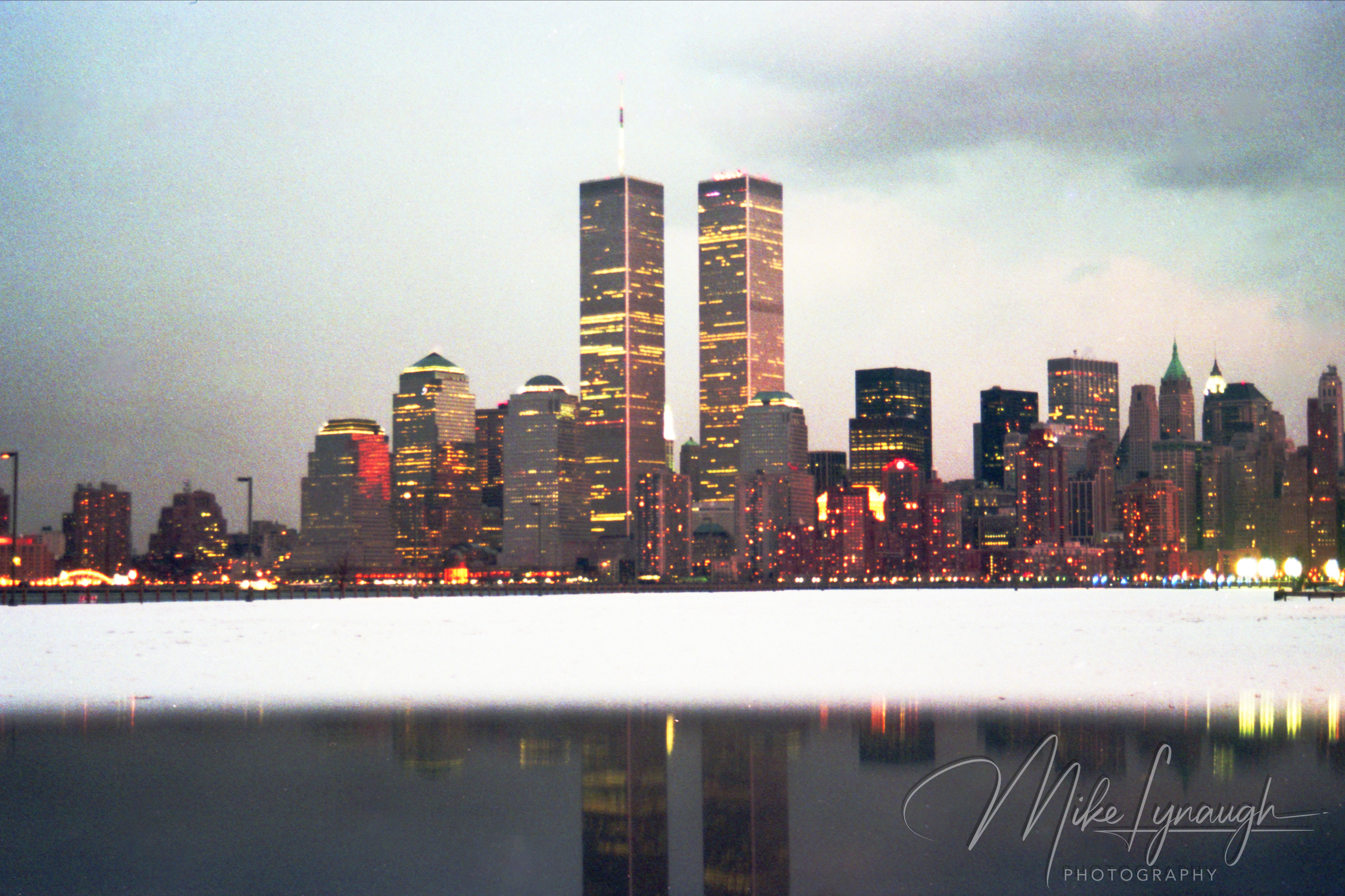 Reflective vehicle surface photo of illuminated Twin Towers and Lower Manhattan skyline across Hudson River in March 1992
