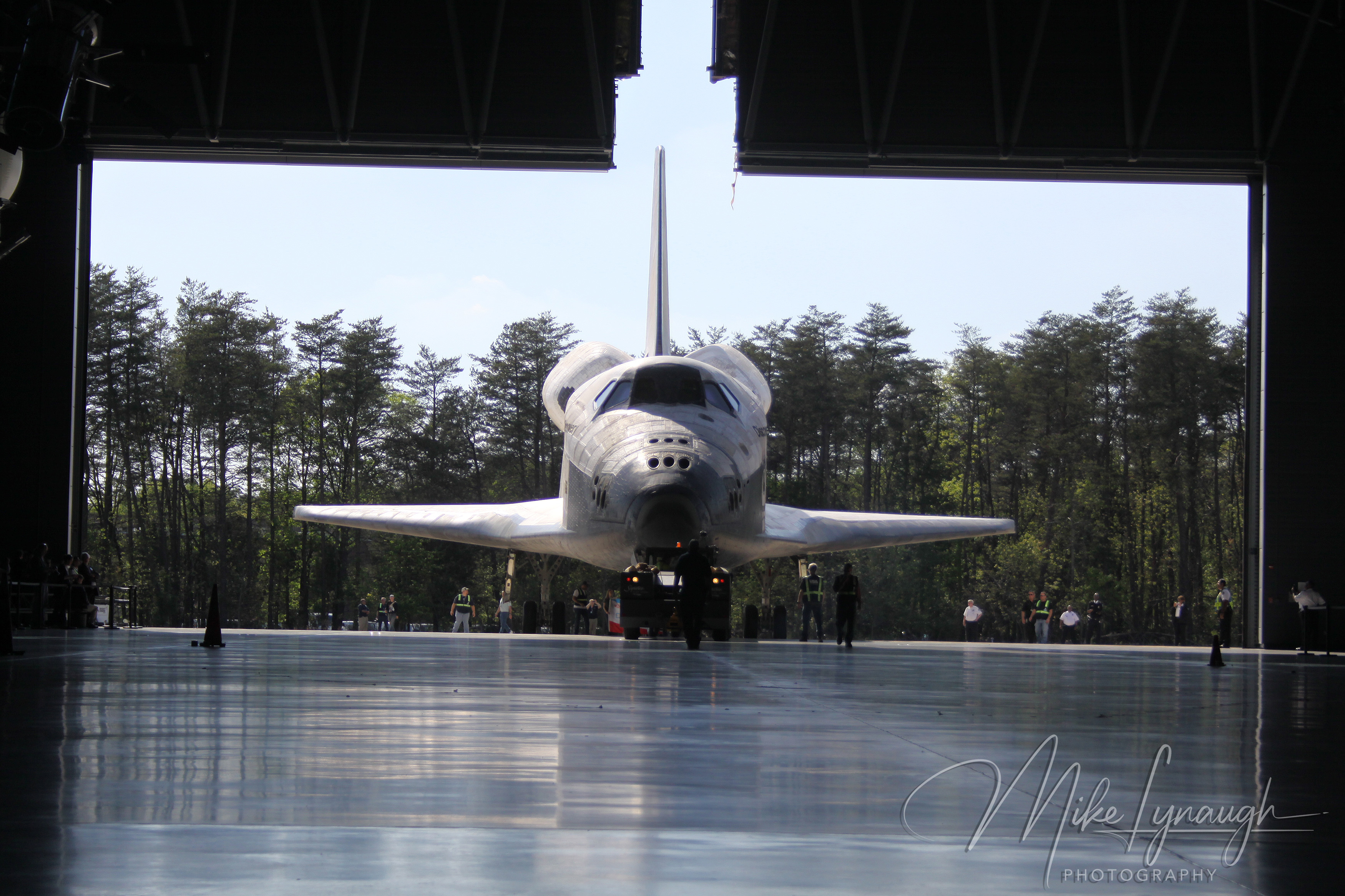 A wide-angle interior photograph capturing Space Shuttle Discovery (OV-103) head-on as she is towed through the open doors of the James S.