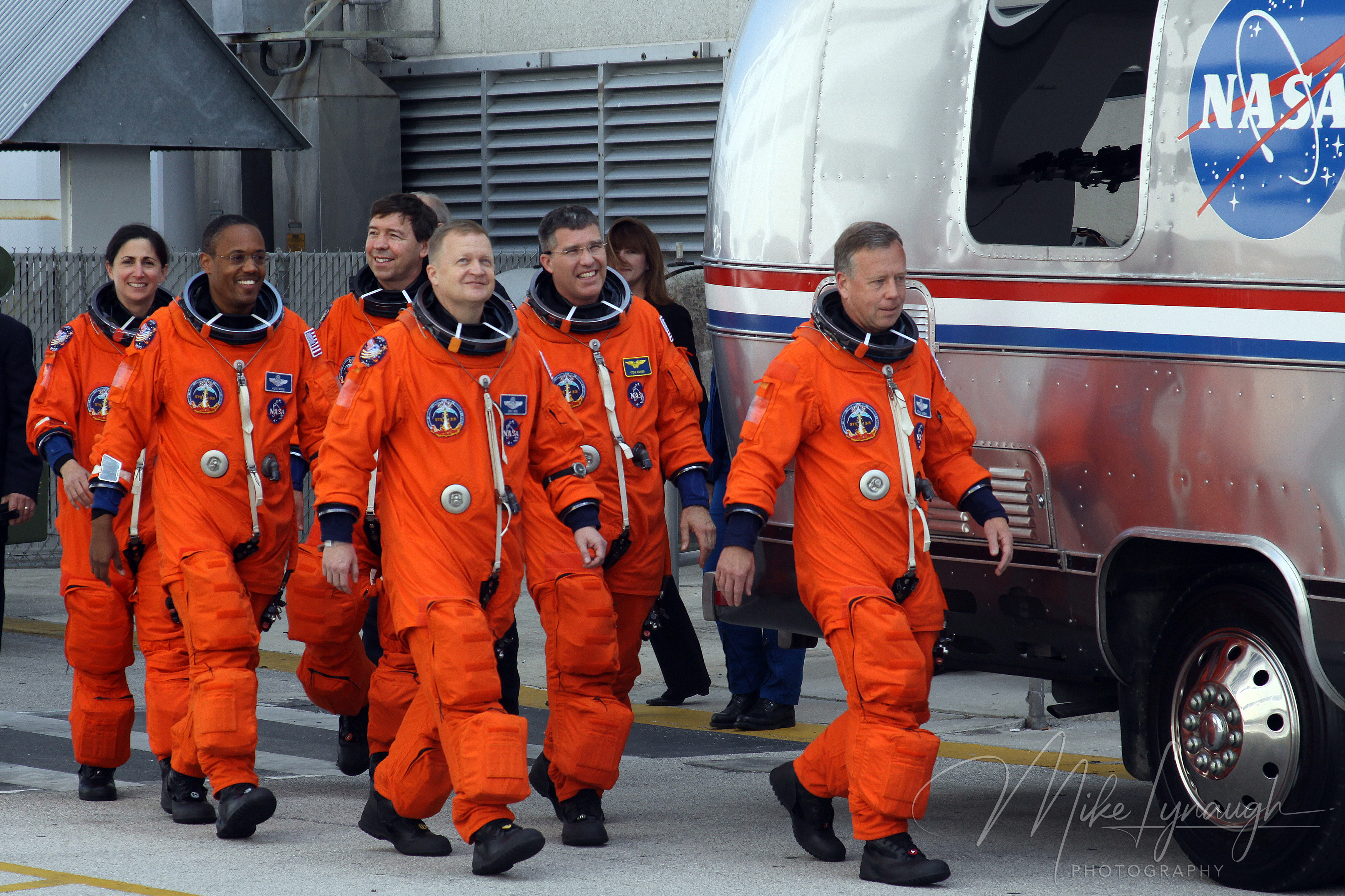 Astronauts Commander Steve Lindsey leading the STS-133 crew in their orange Advanced Crew Escape Suits (ACES) as they walk out to the iconic NASA Astrovan outside the Operations and Checkout Building at Kennedy Space.